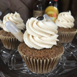 Three coffee flavored cupcakes with pipettes of Kahlua stuck into sides